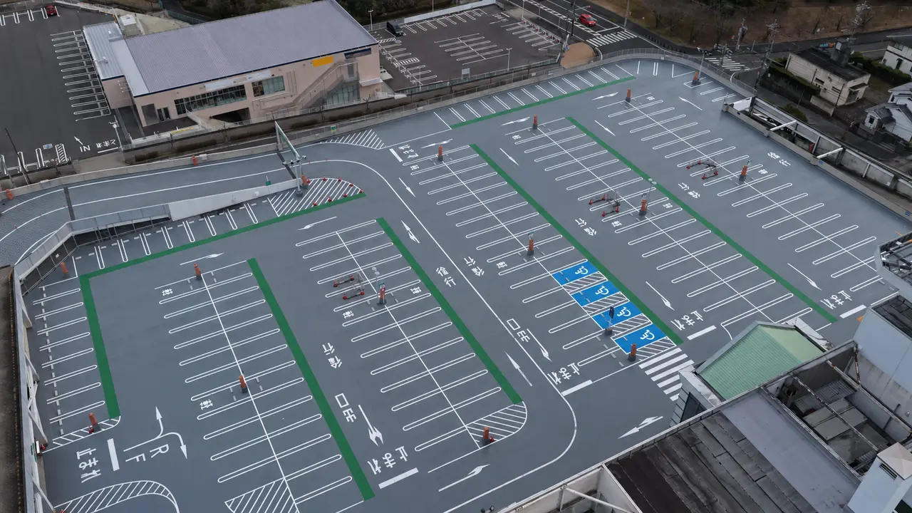イオン瀬戸みずの店の屋上駐車場。白線、誘導矢印、緑色の通路、スロープを見渡す改修後の空撮写真